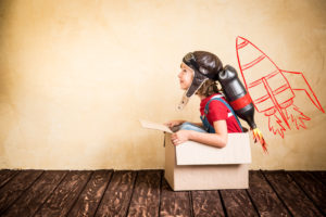 child playing in cardboard box rocket suggests older adults can still be creative and learn to fly in second childhood
